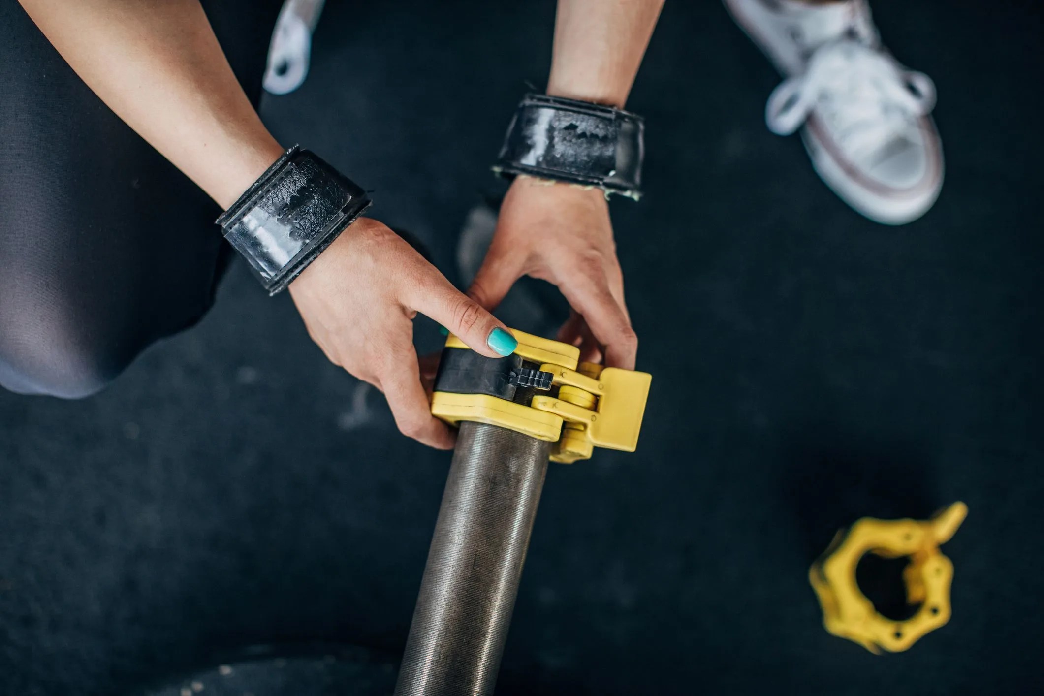 female putting safety lock on barbell in gym