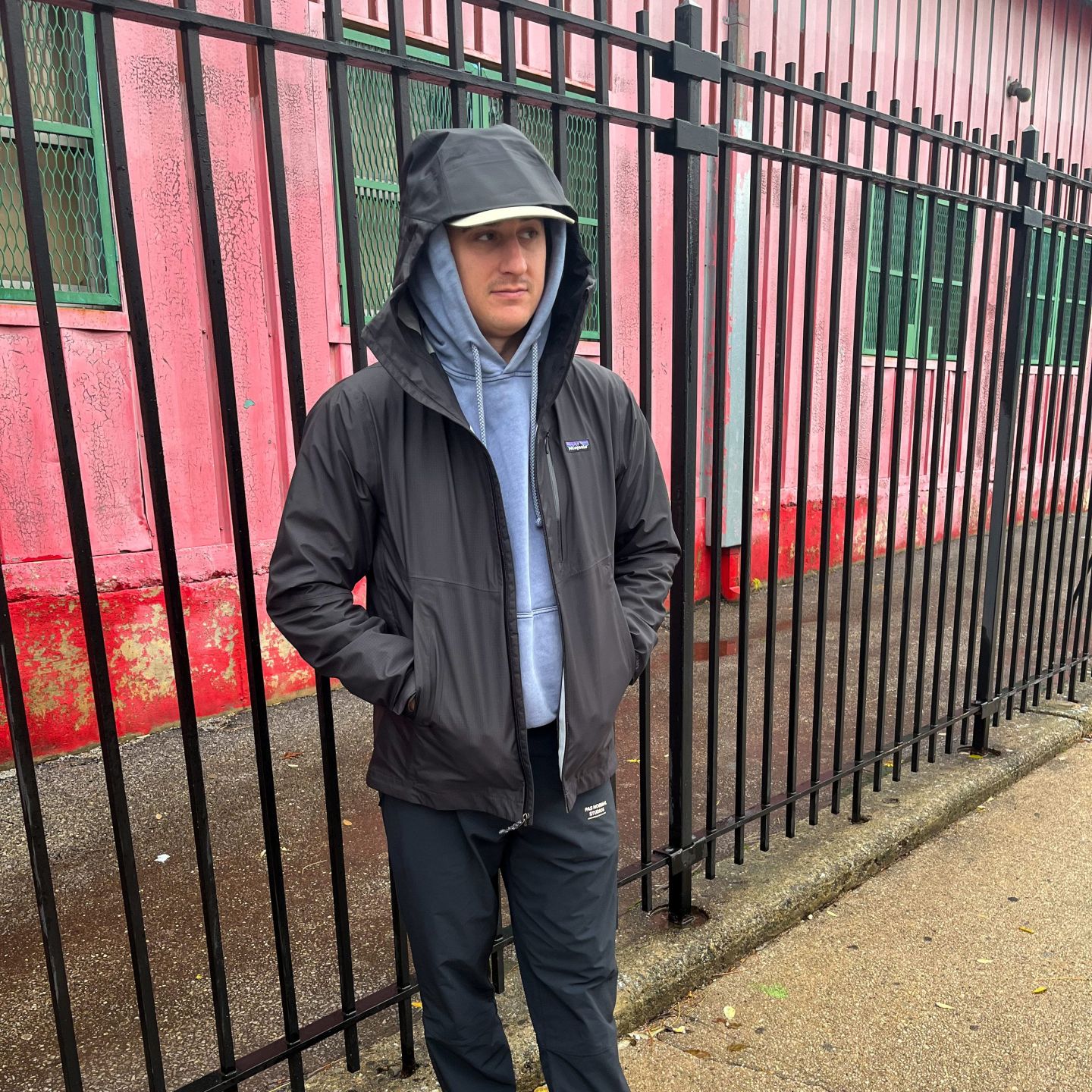 man standing by a fence wearing a patagonia rain jacket