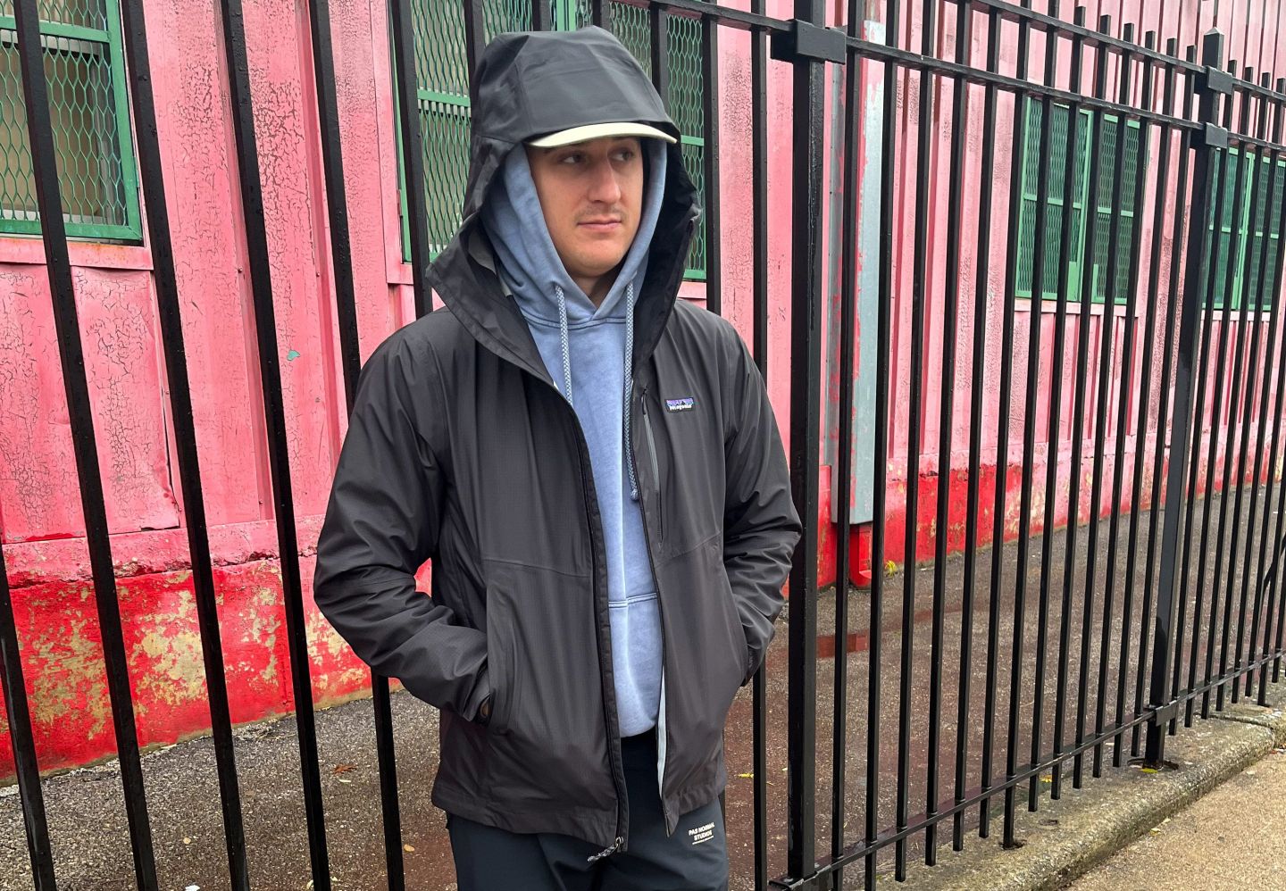 man standing by a fence wearing a patagonia rain jacket
