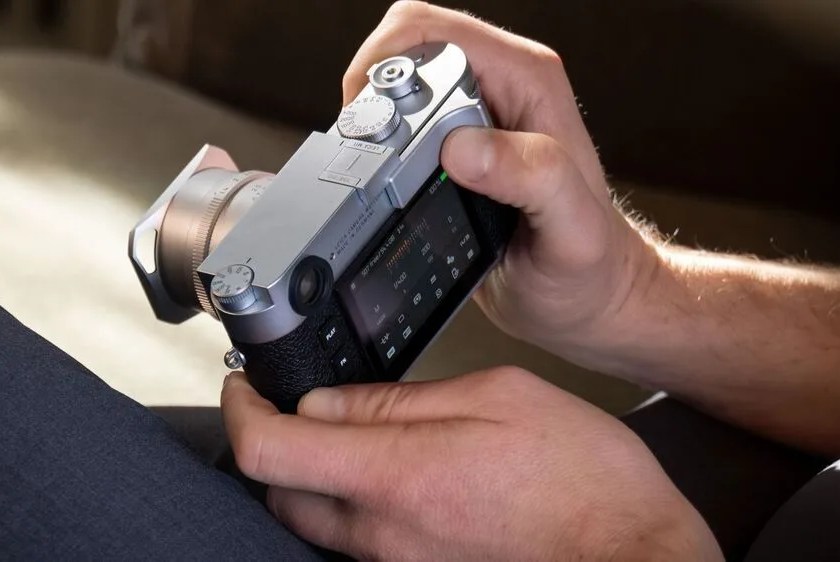 someone holding a mirrorless camera and looking at the screen