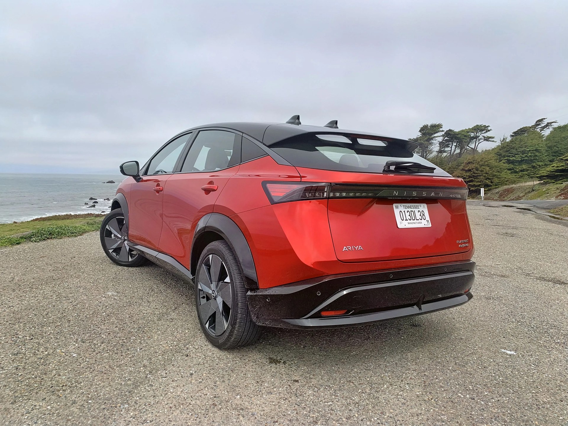 2023 nissan ariya from rear quarter panel parked next to pacific ocean