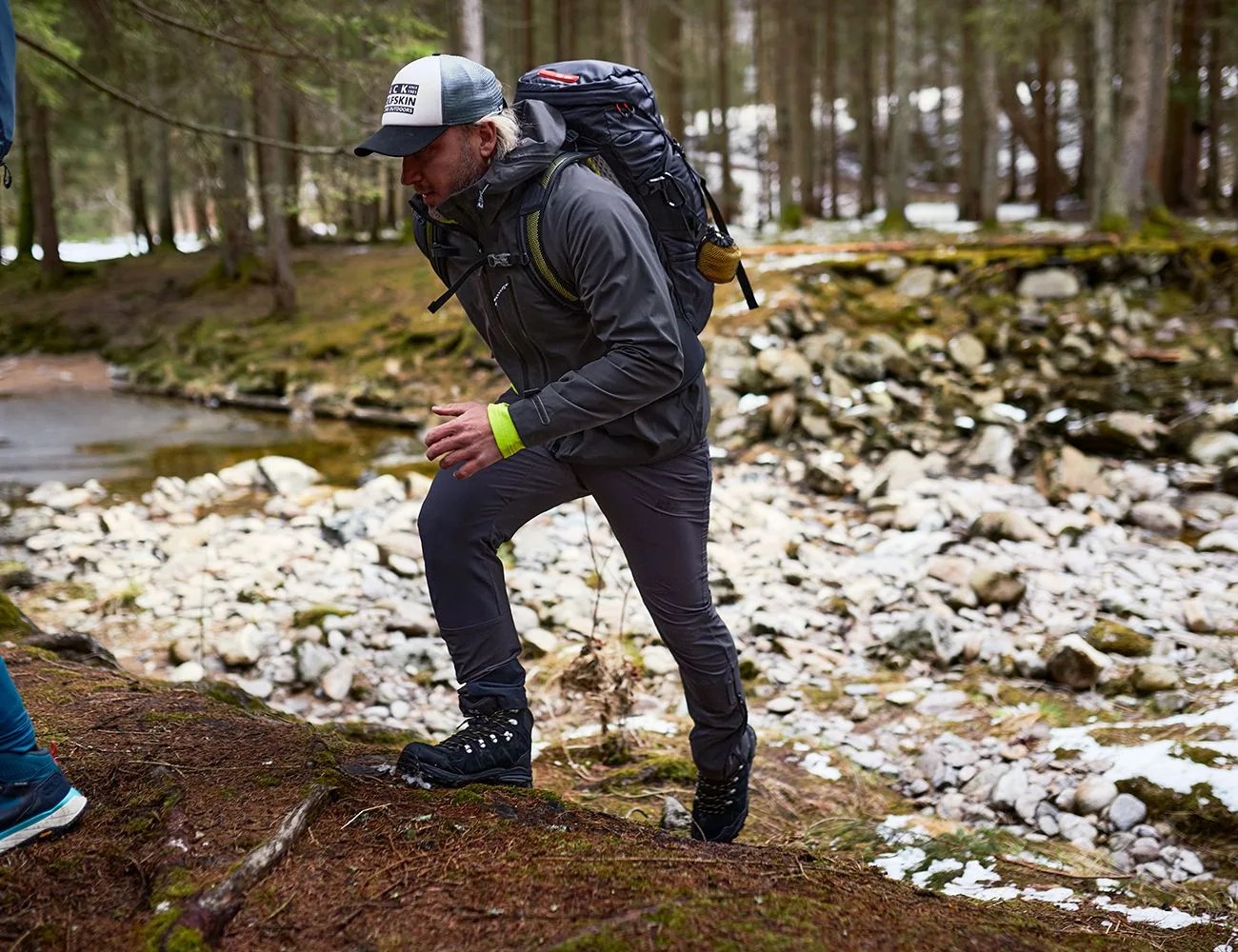 a man hiking wearing a black jack wolfskin jacket and white hat
