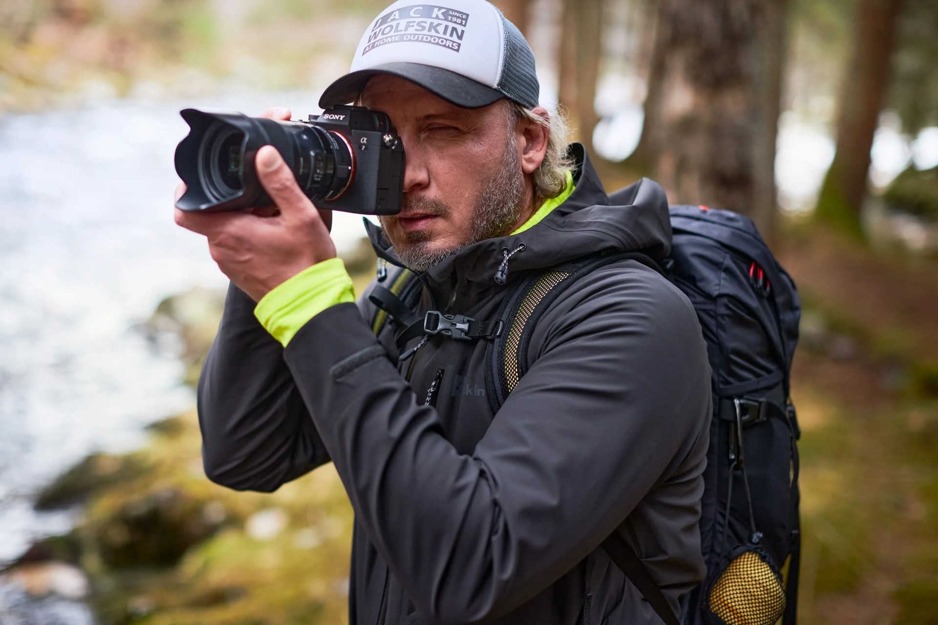 a man taking a photo in the wilderness wearing a black jack wolfskin jacket