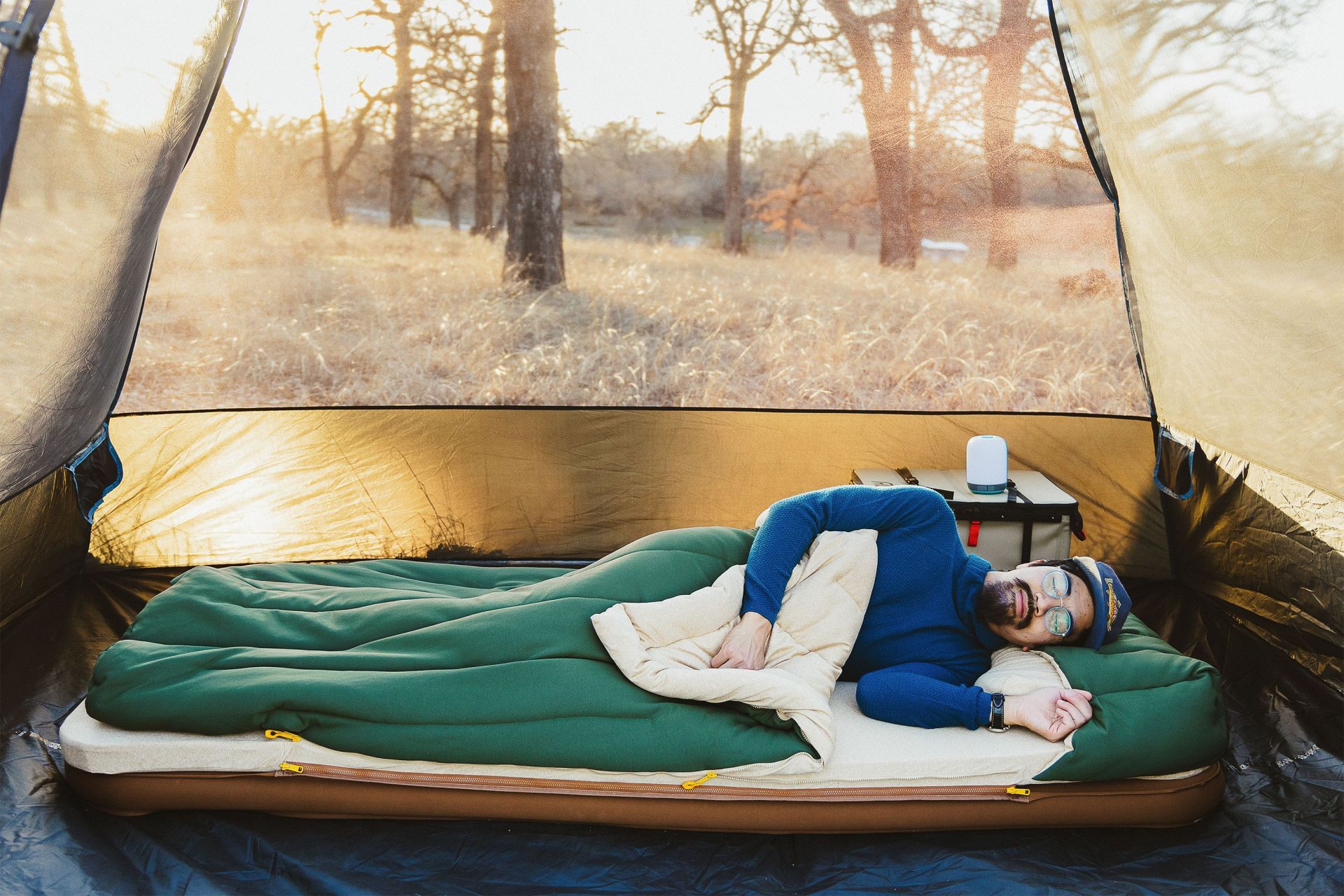 a man sleeping on a mattress in a tent
