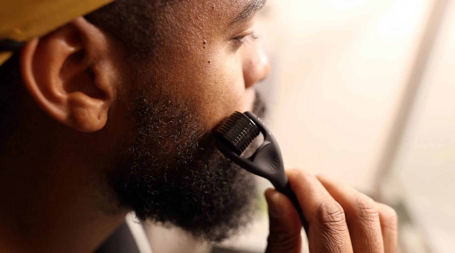 a man using a facial roller on his beard