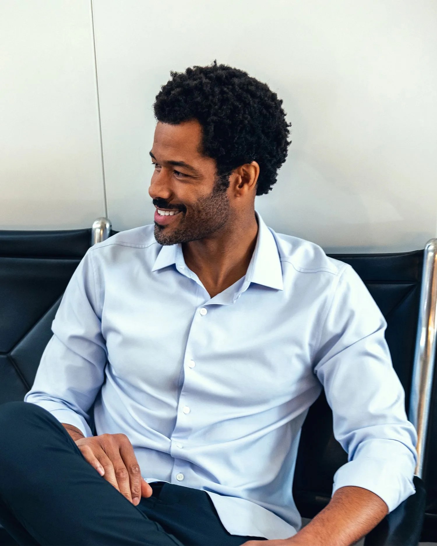a man sitting on a couch wearing a blue button down shirt