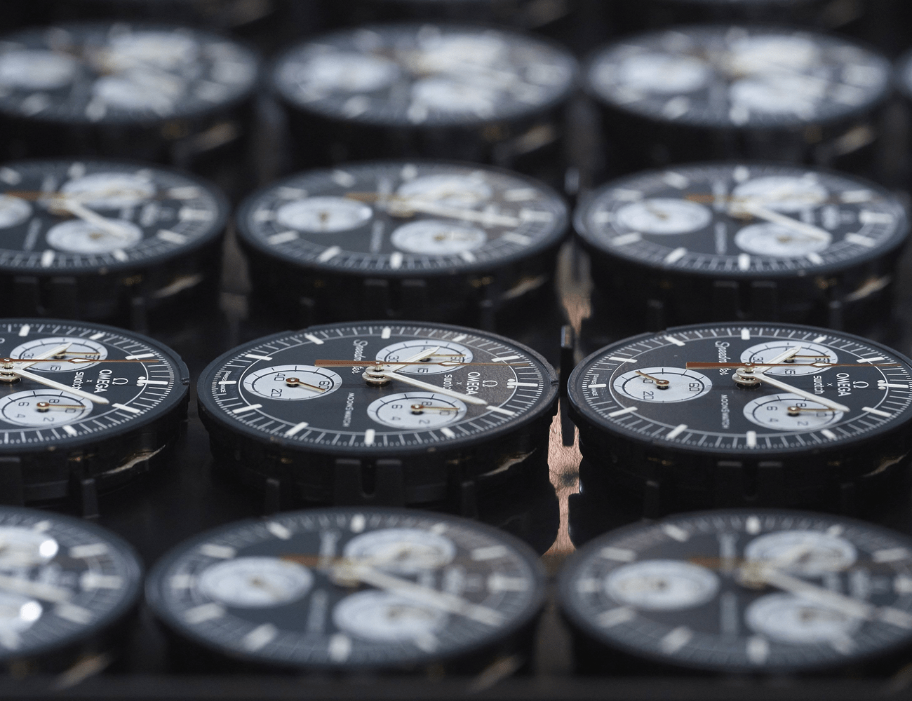 multiple black moonswatch dials laying on a table