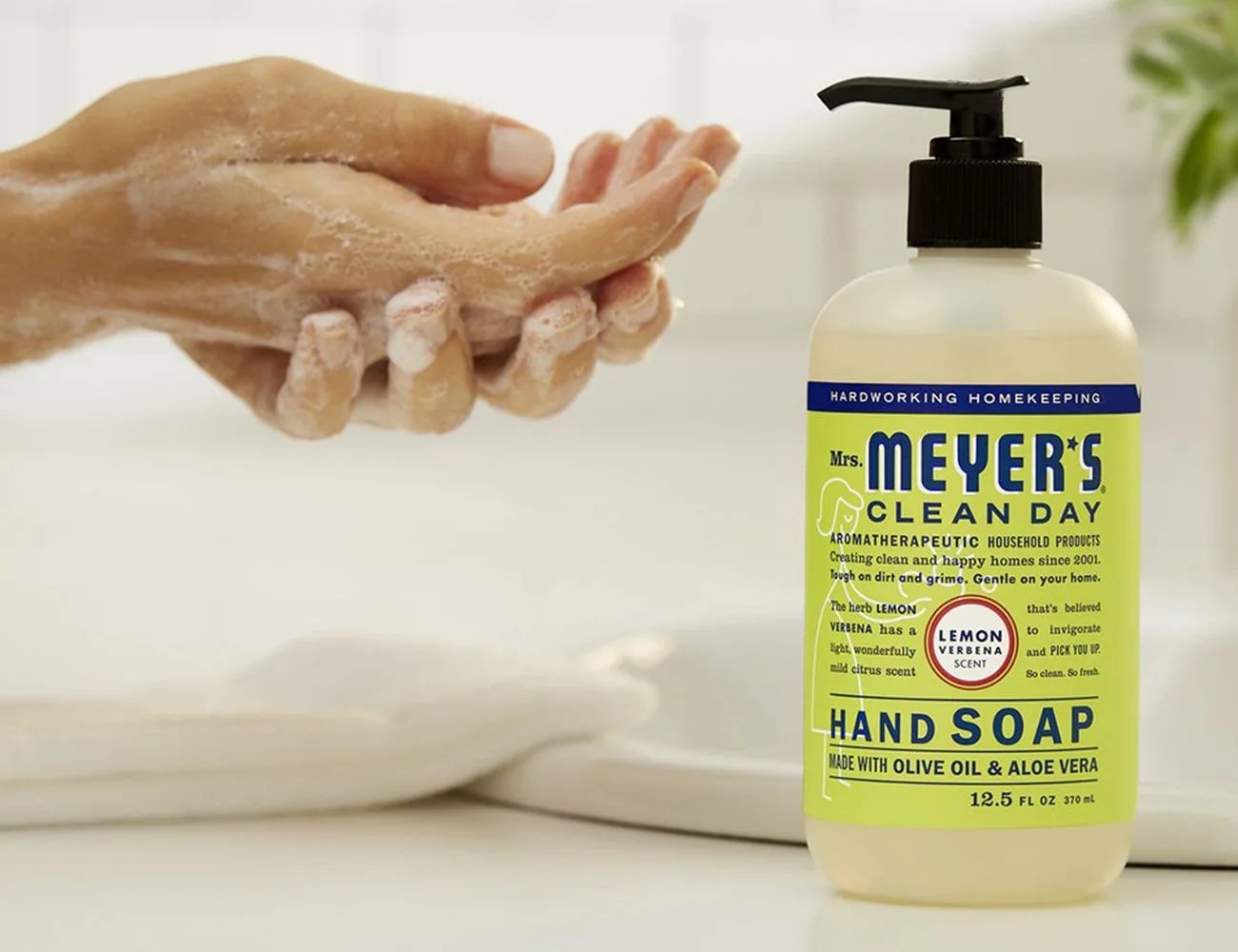 hands washing with soap and a soap dispenser in the forefront