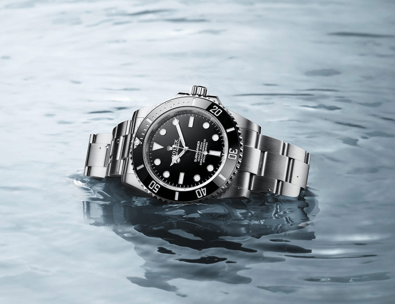 a silver rolex submariner with black dial laying in blue water