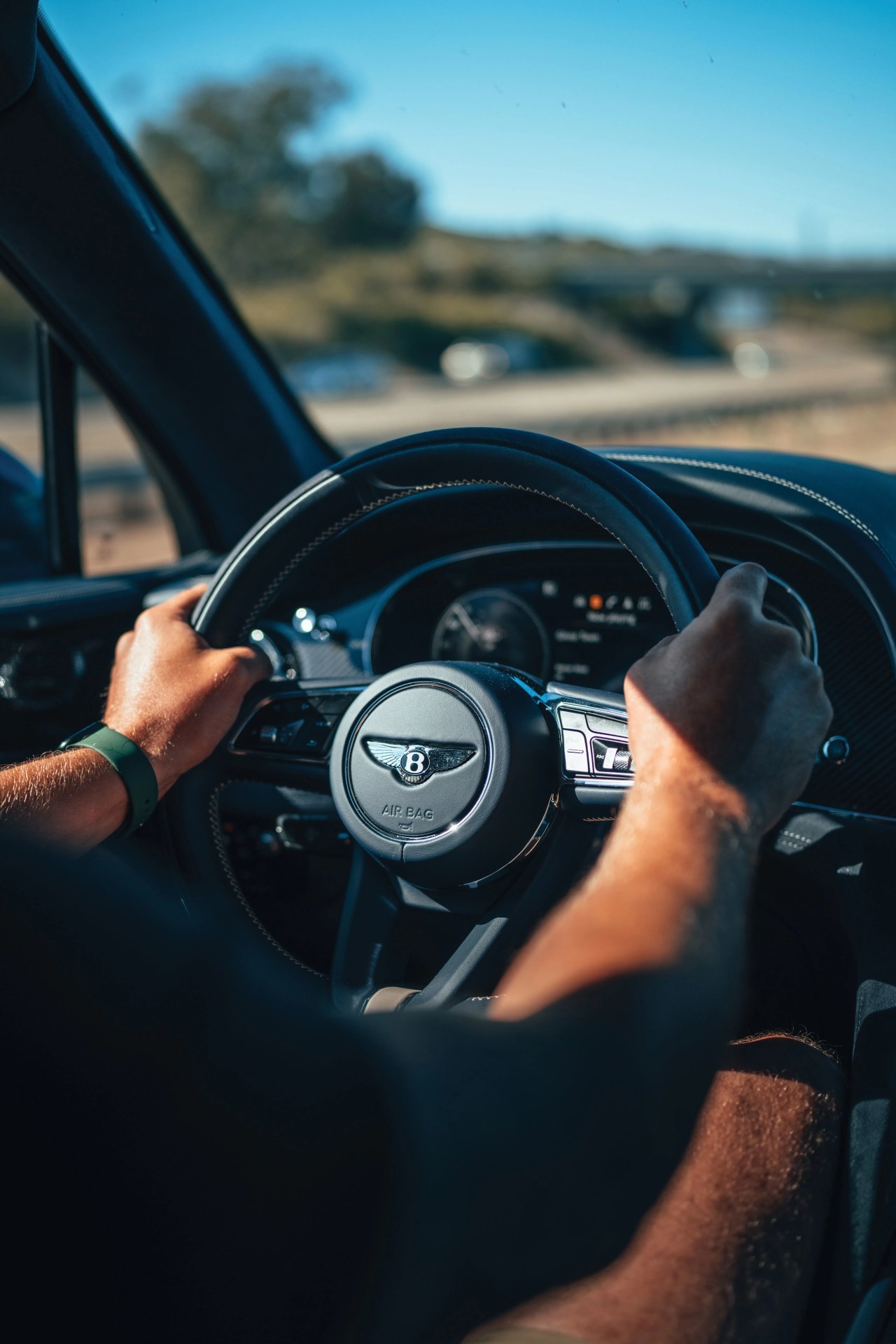 someone in the drivers seat driving a bentley with hands on the wheel