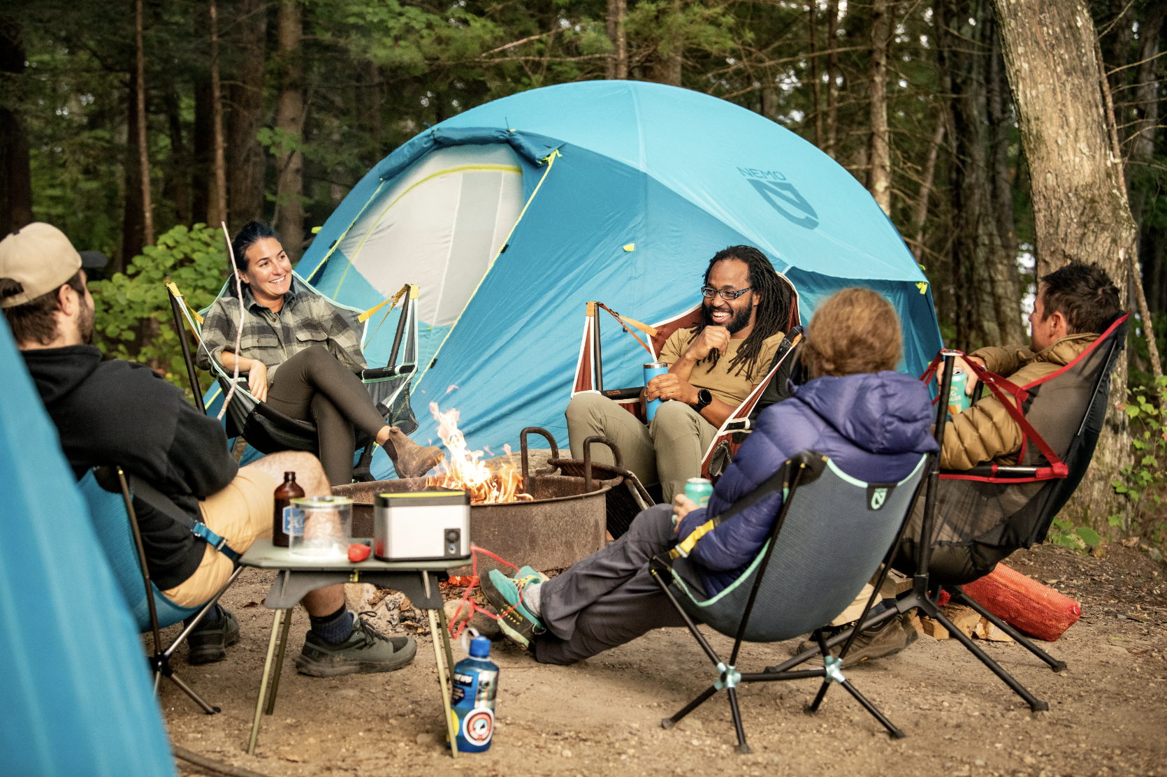 people sitting around fire in camping chairs