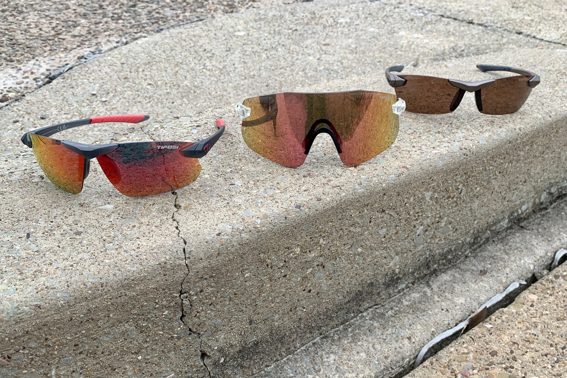 three pairs of tifosi sunglasses sitting on a curb