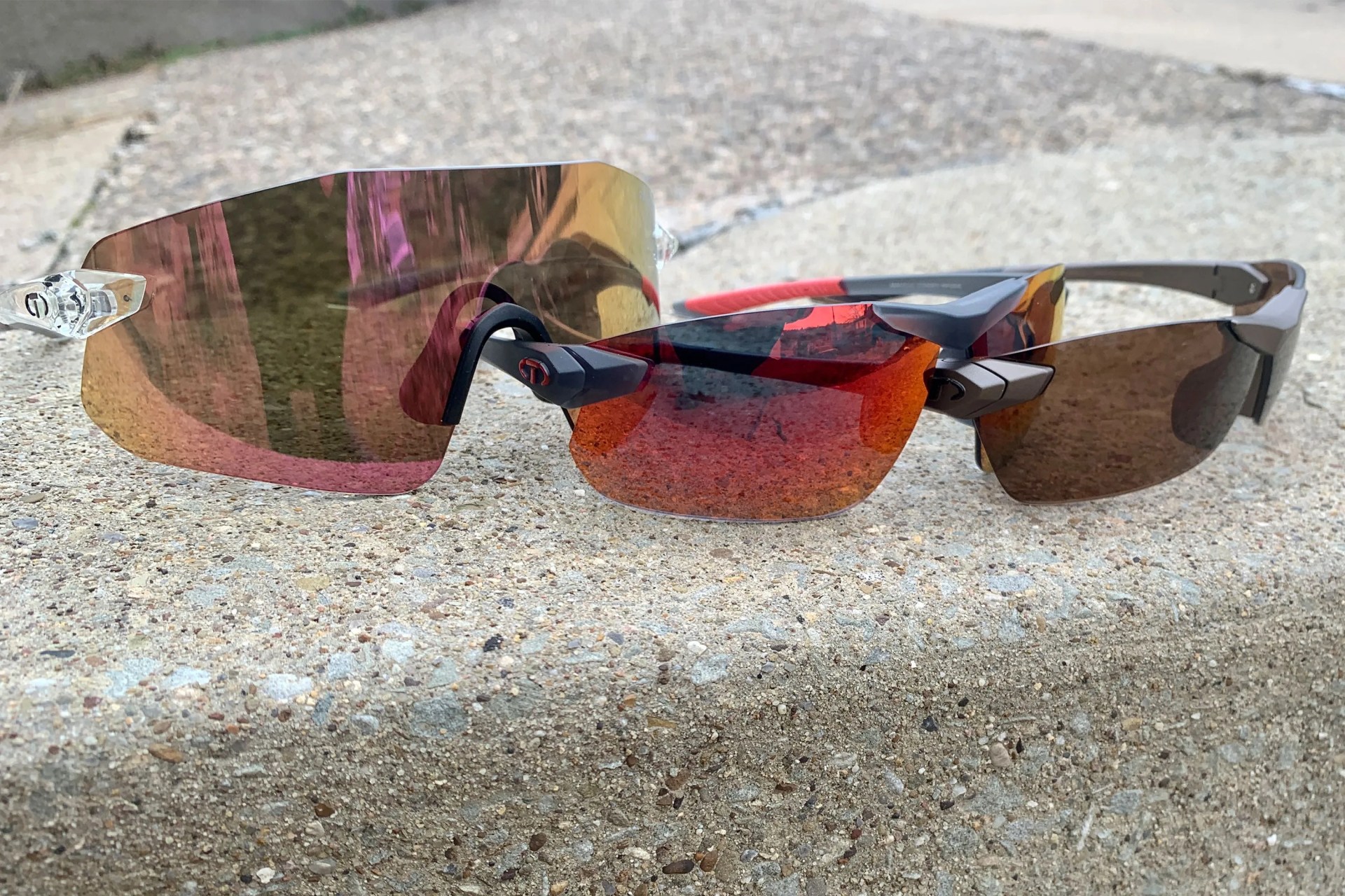 three pairs of tifosi sunglasses on a cement curb