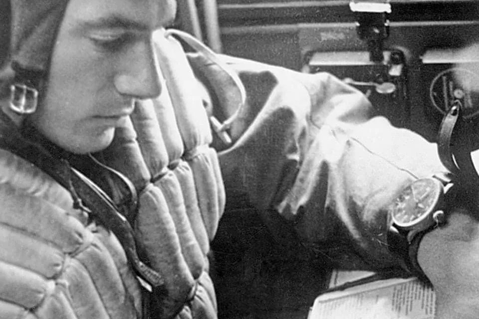 a black and white photo of a pilot wearing a pilots watch