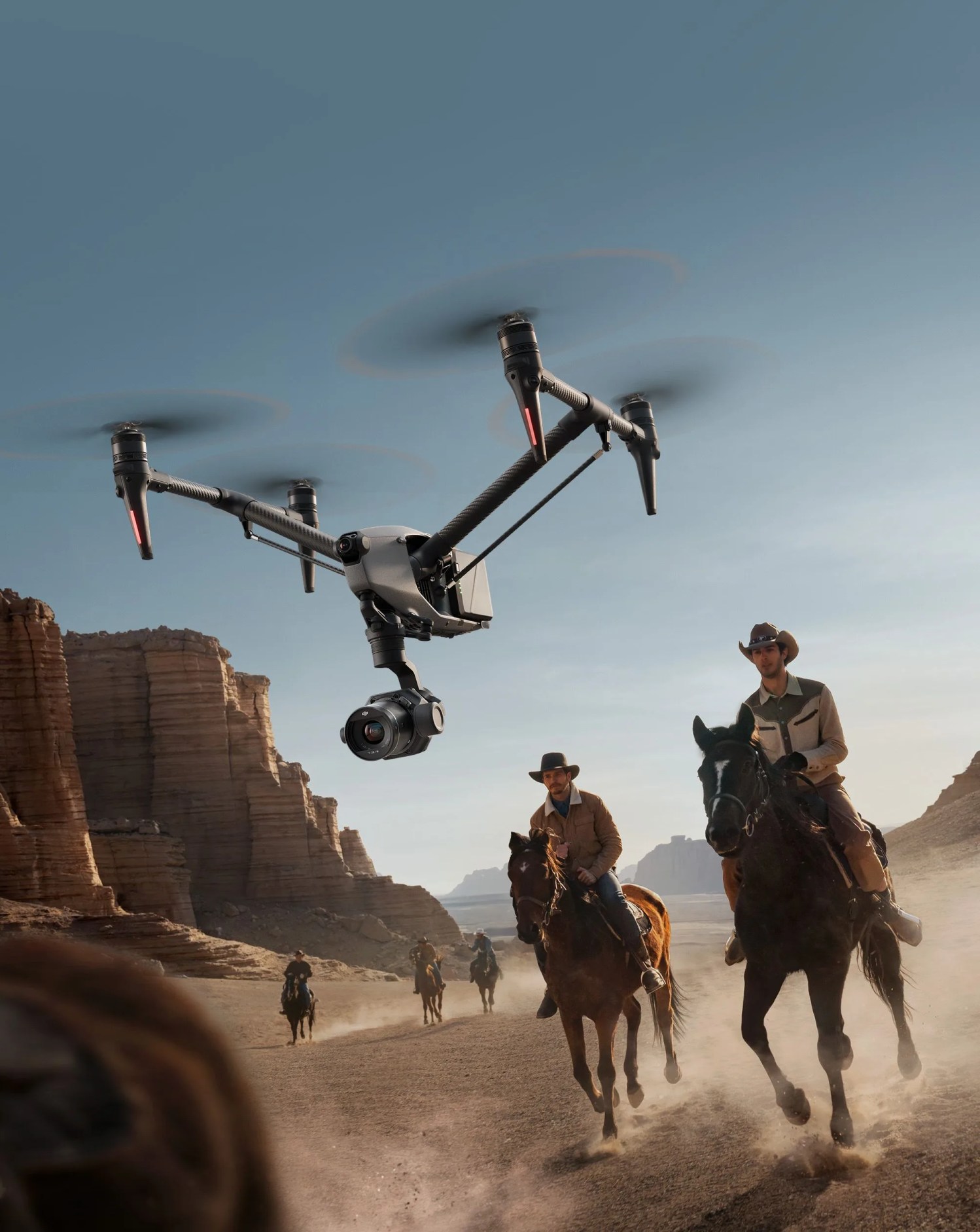 dji inspire 3 drone following two men riding on horseback through canyon