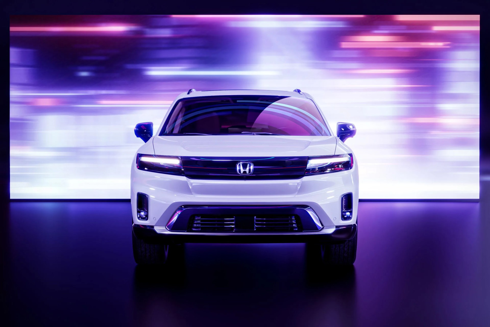 2024 honda prologue viewed from the front with blurred city lights on a screen in the background