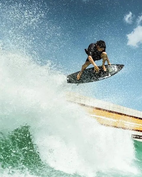 man surfing while wearing billabong x keith haring clothing