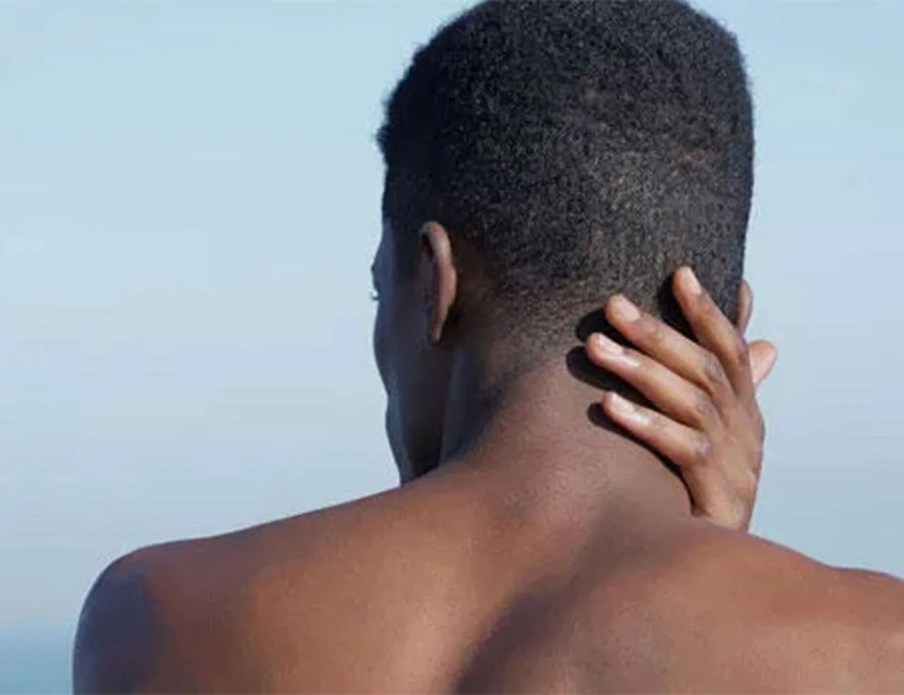 man touching the back of his hairline