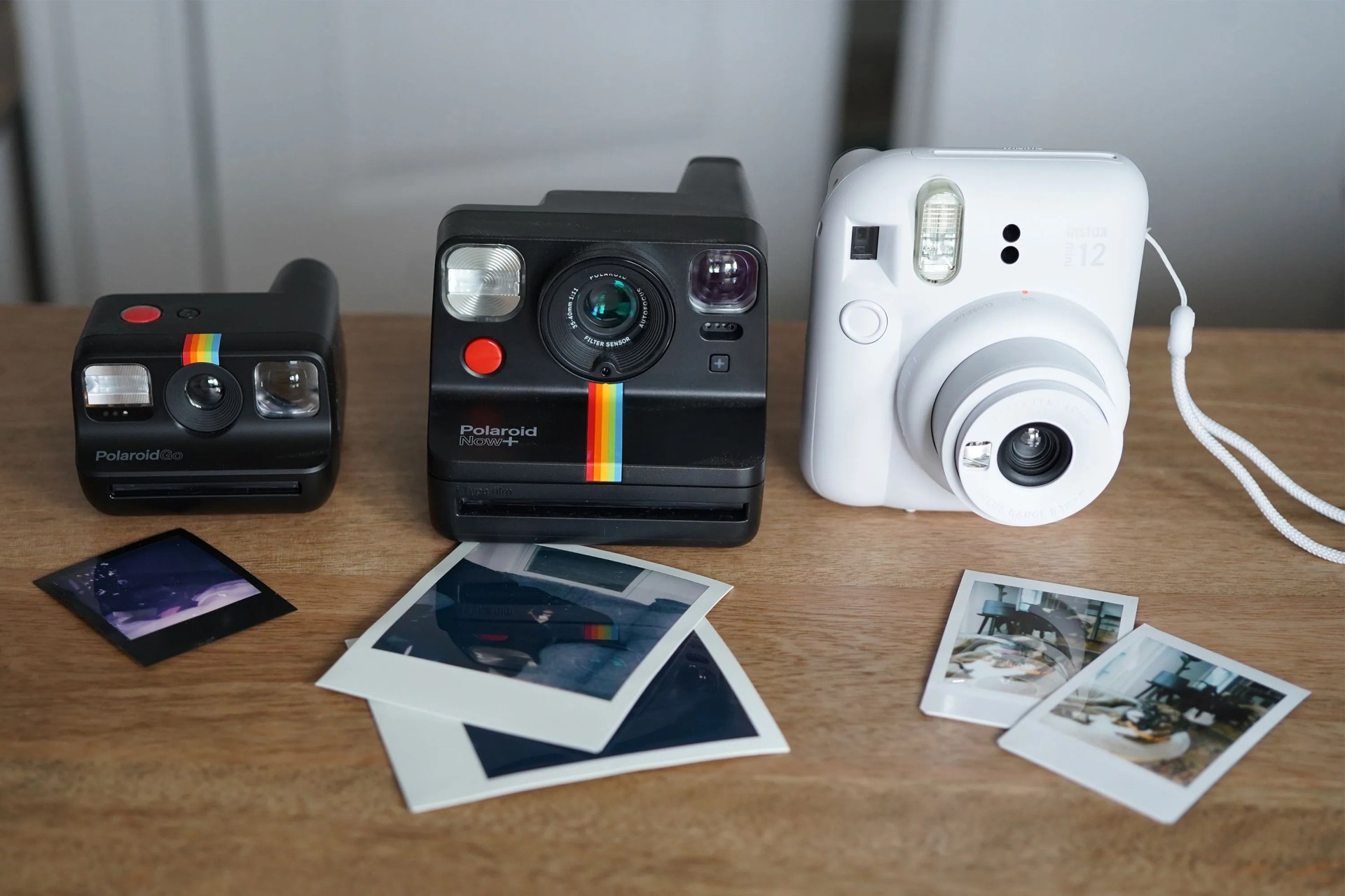 three instant cameras on a table with photos that were taken with them