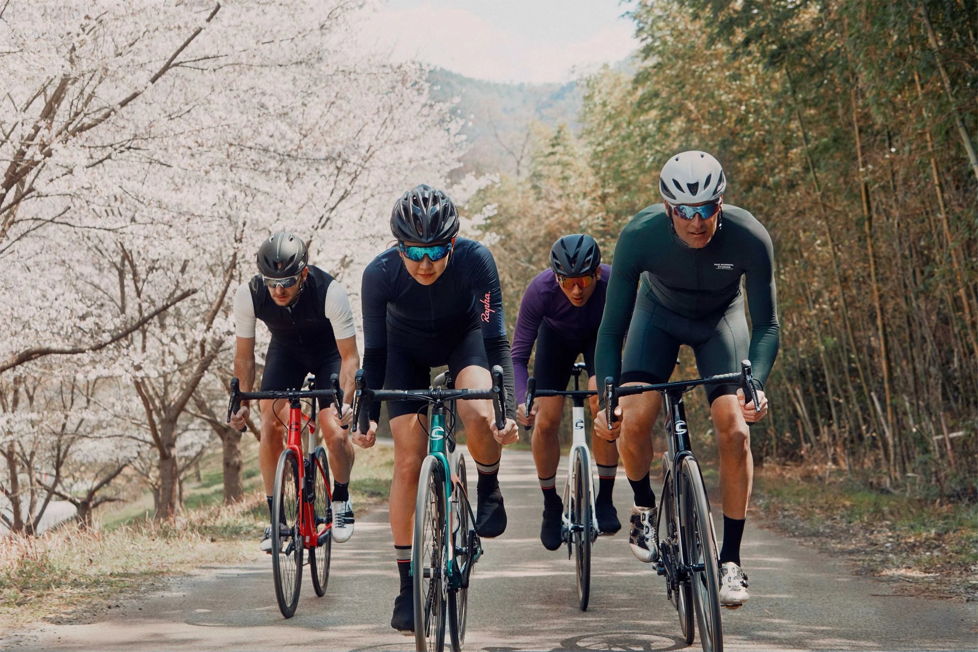 a group of bikers riding down a paved bike path