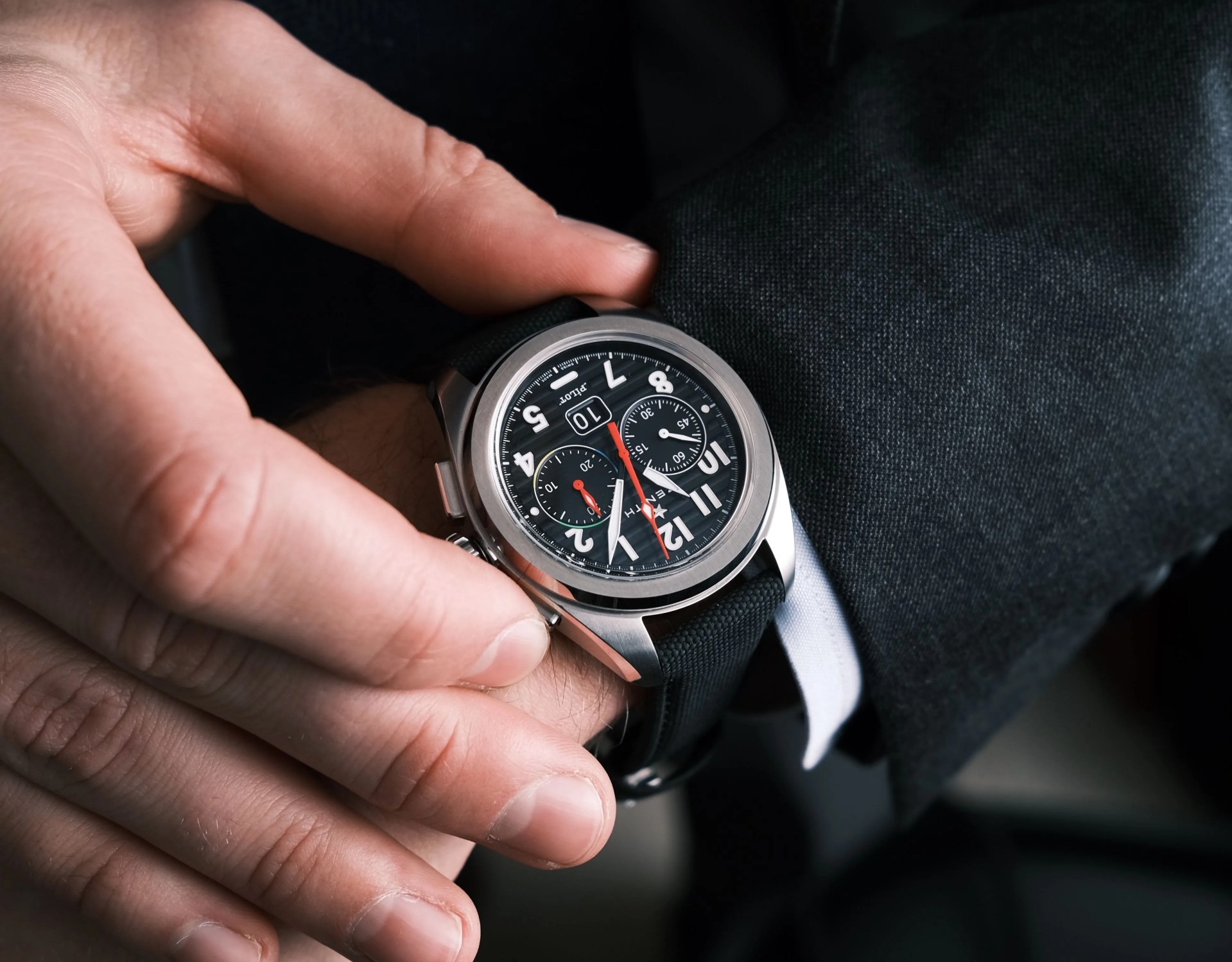 the zenith pilot big date flyback watch on the wrist of a man wearing a suit