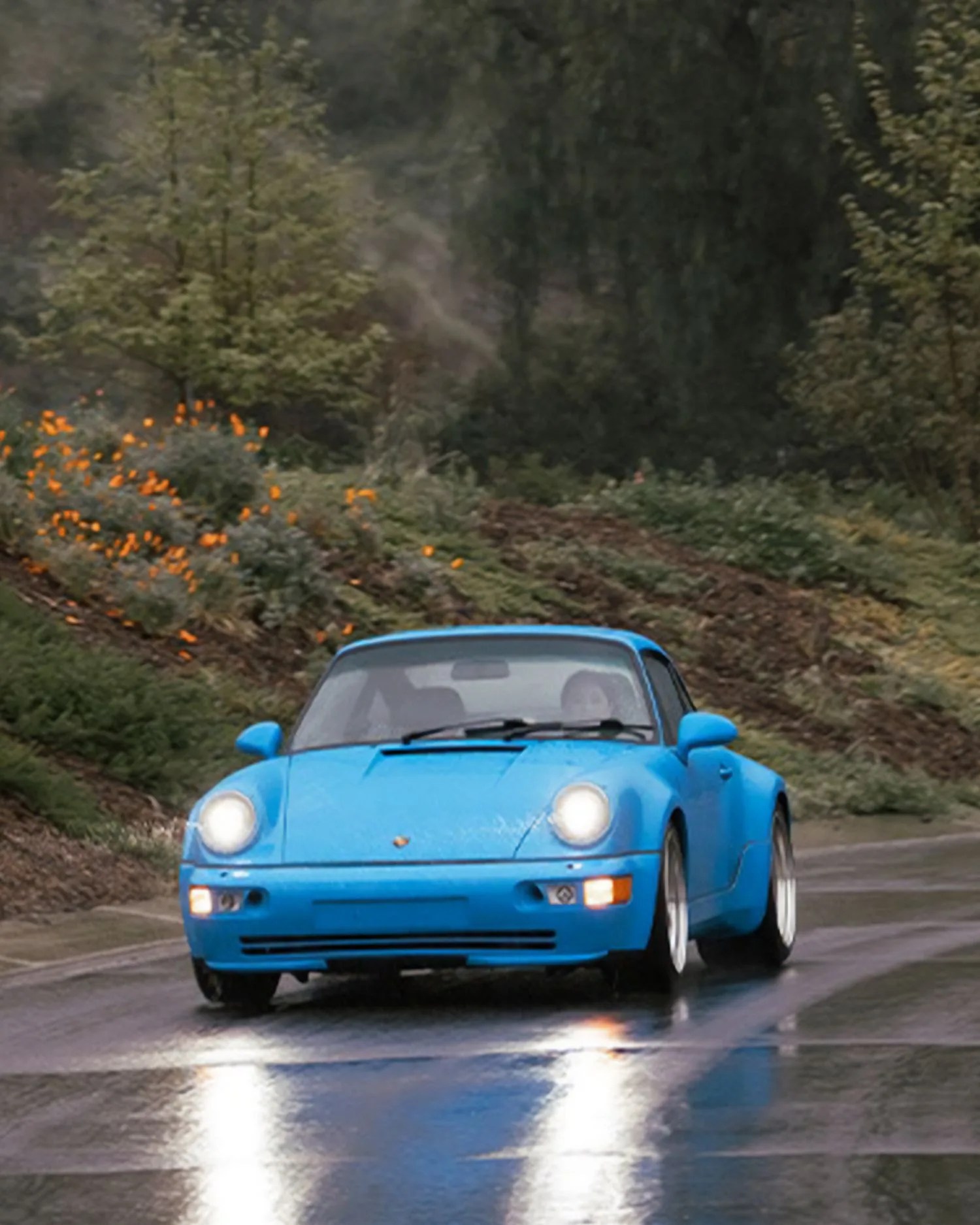 a blue porsche driving on a road
