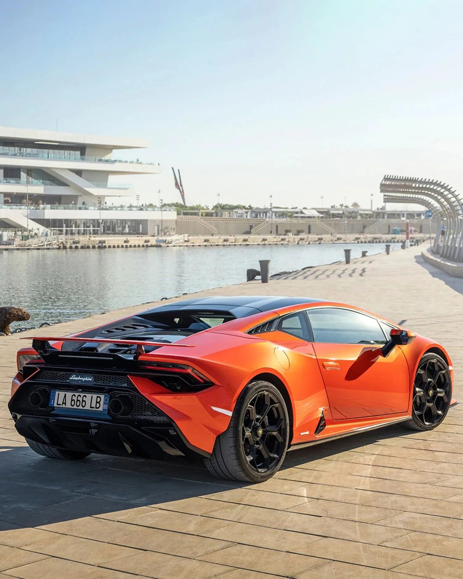 an orange lamborghini parked by a bay