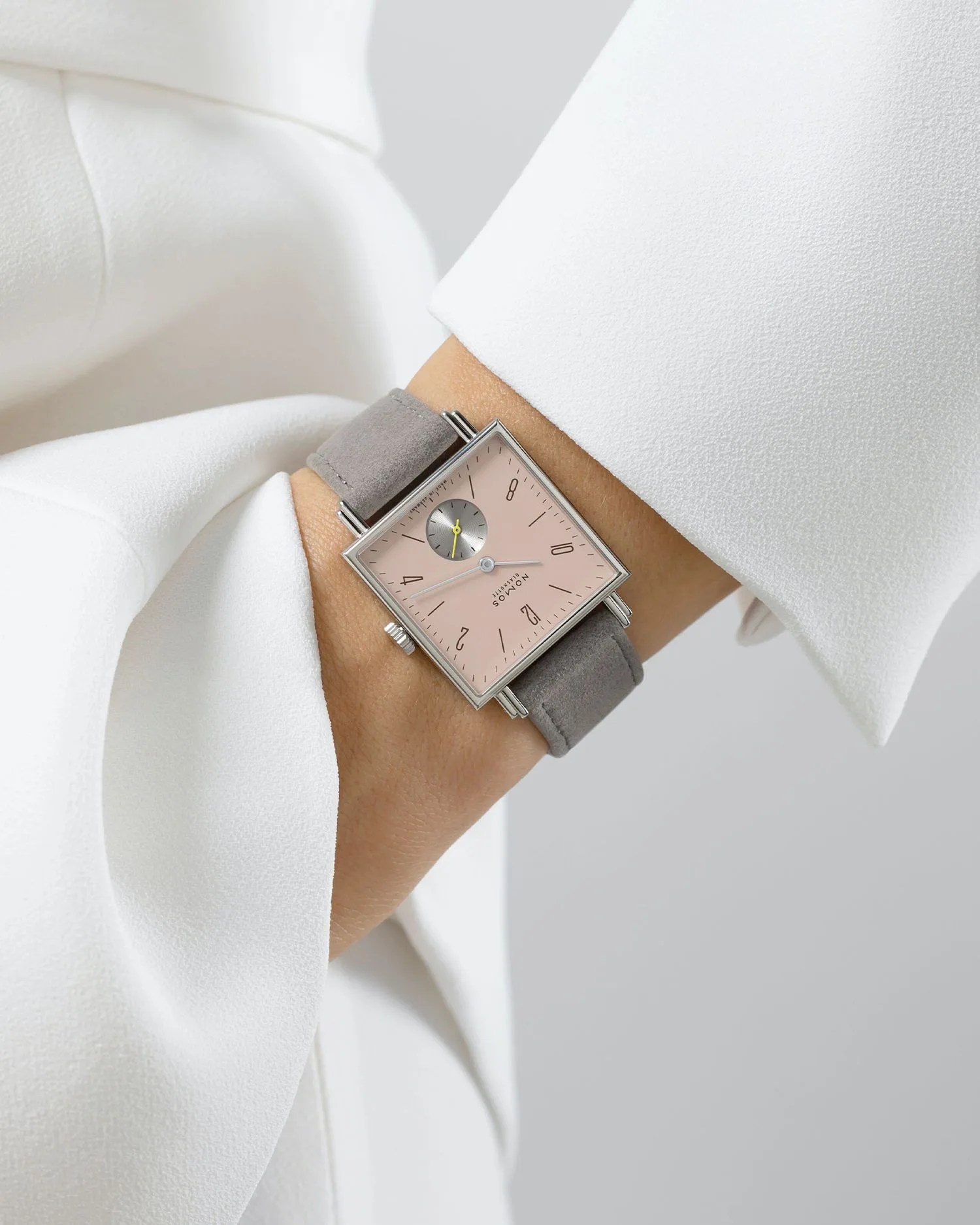 a close up of a womens wrist wearing a watch in a white outfit
