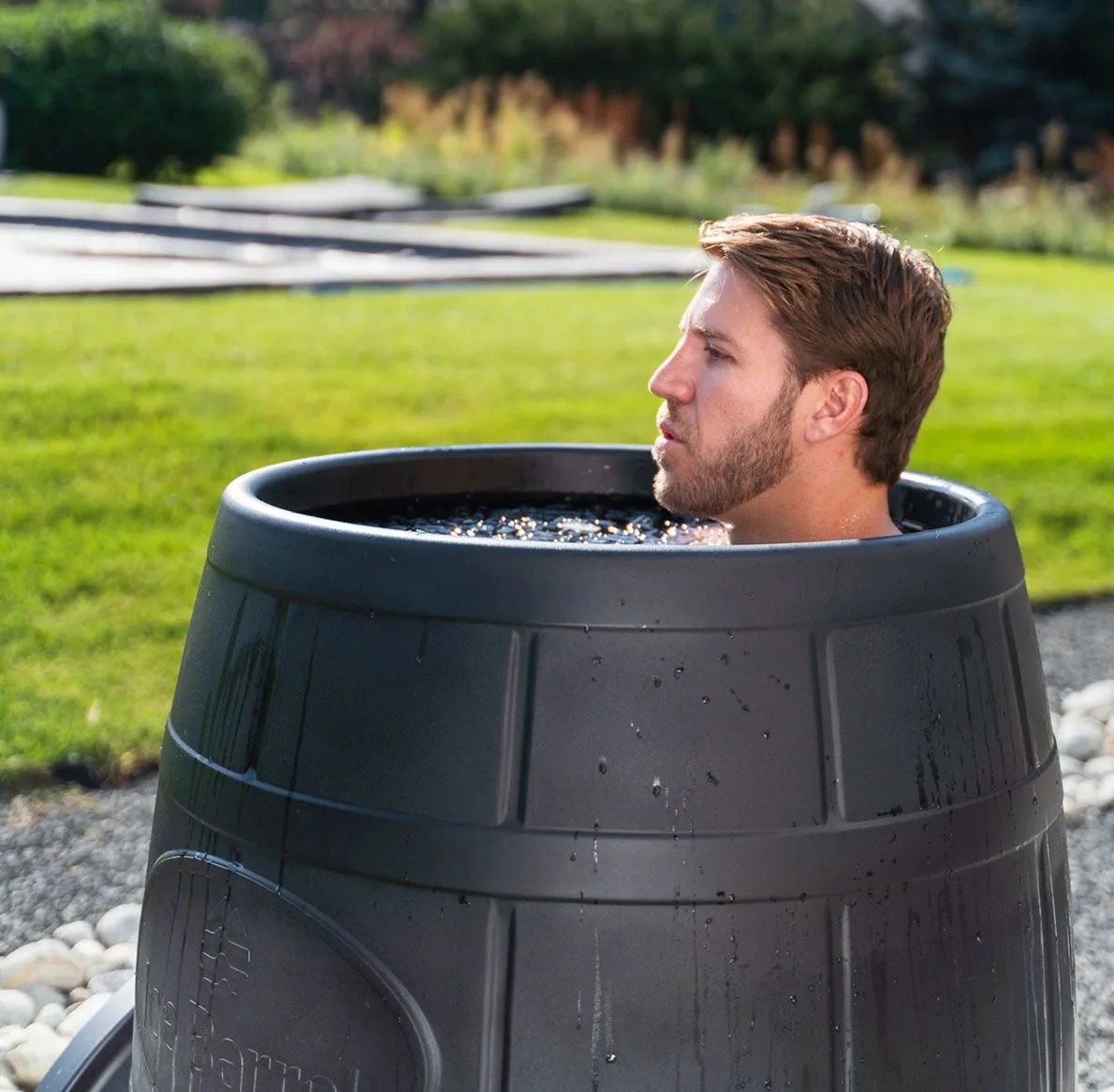 a man sitting in a barrel of ice outside