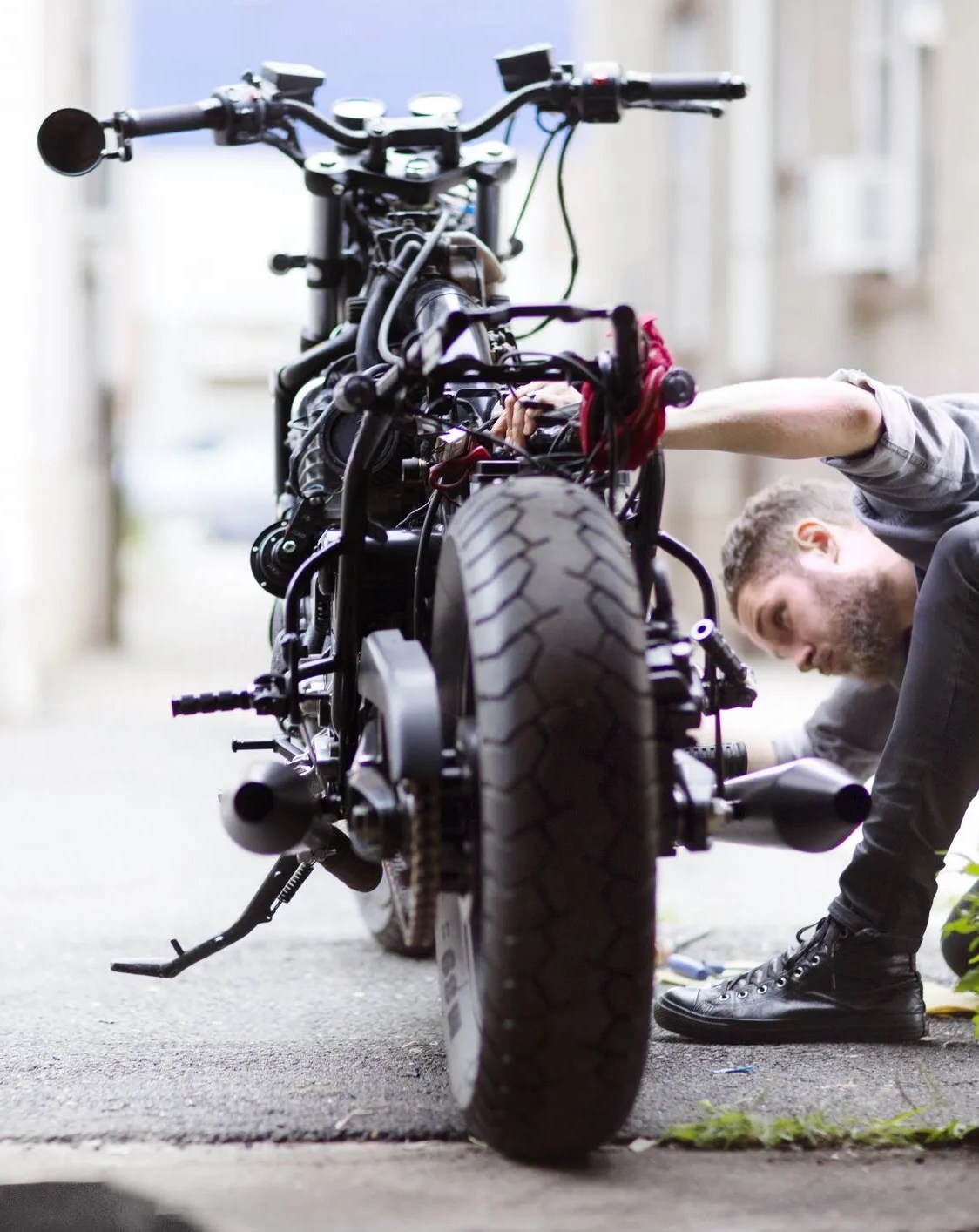 man looking at a motorcycle outside of a garage