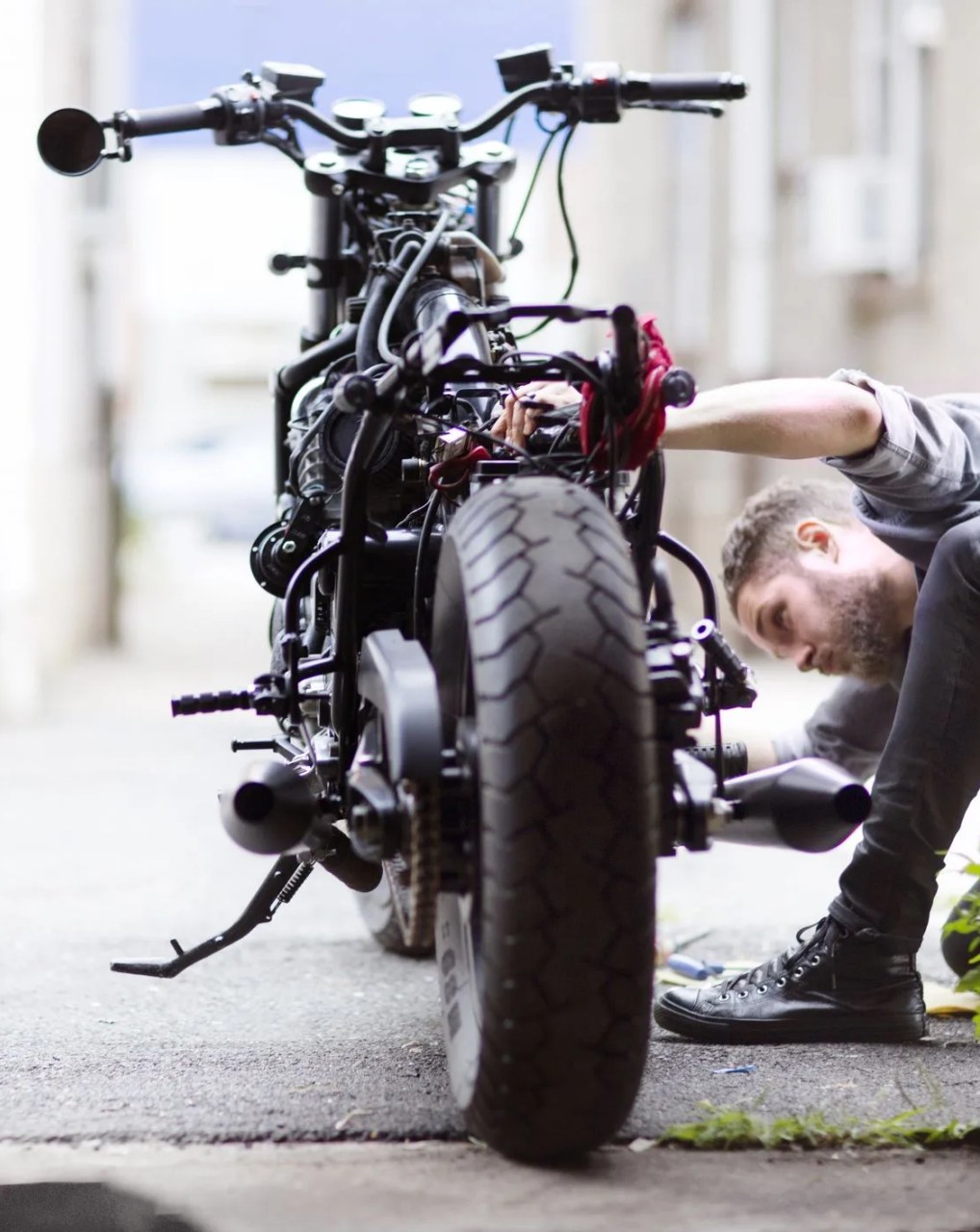 man looking at a motorcycle outside of a garage