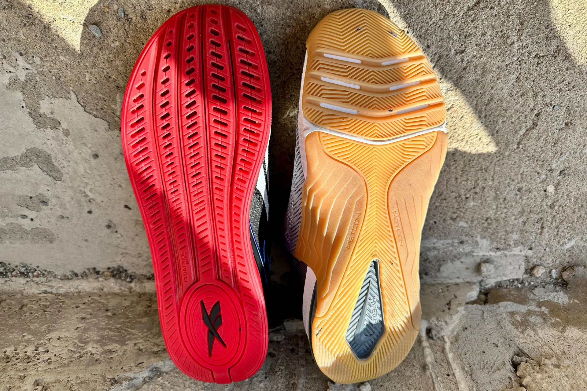 the soles of a nike shoe and reebok shoe sitting side by side on a sidewalk