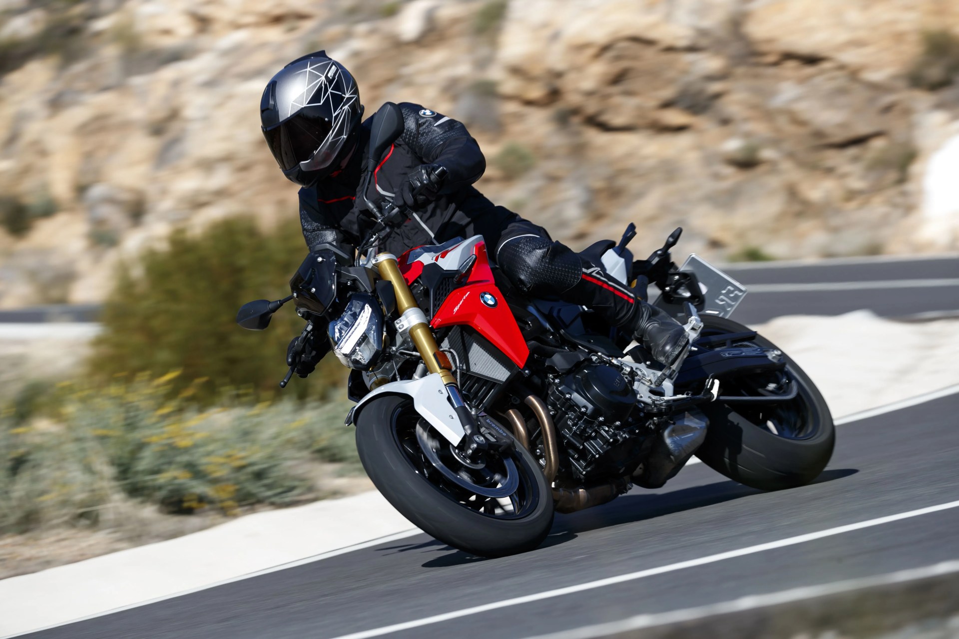 bmw f 900 riding around a corner with rocks in the background