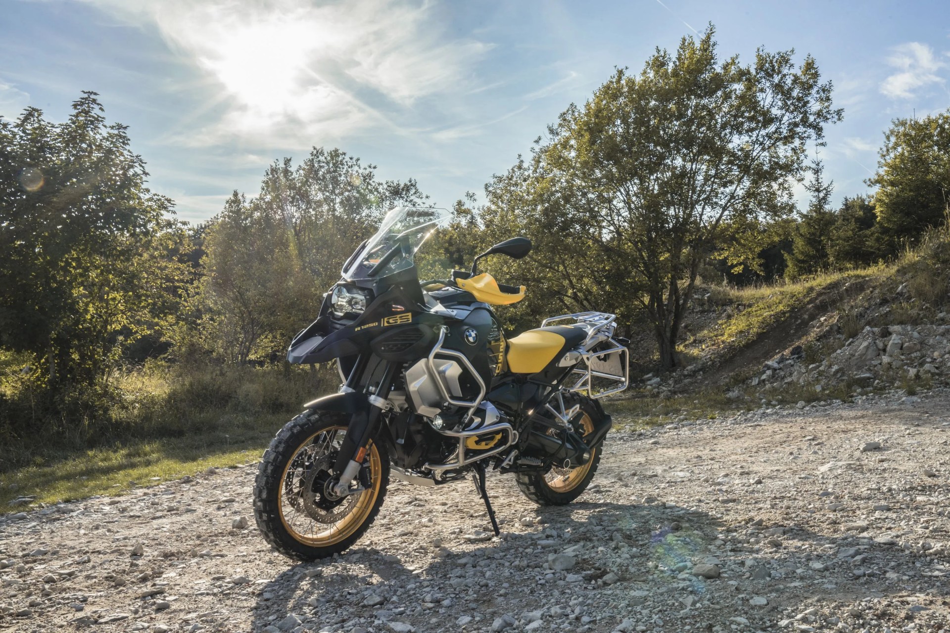 bmw r 1250 gs parked in the dirt with woods in the background
