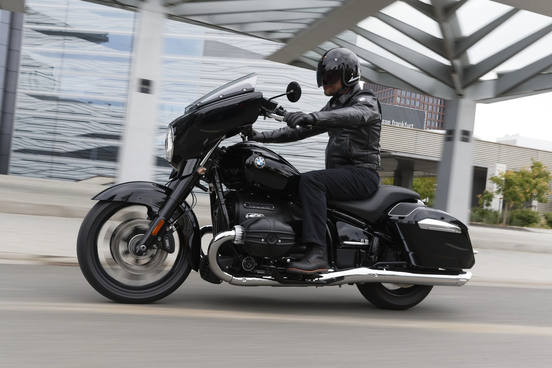bmw r18 riding on the street in germany with an arty looking building in the background