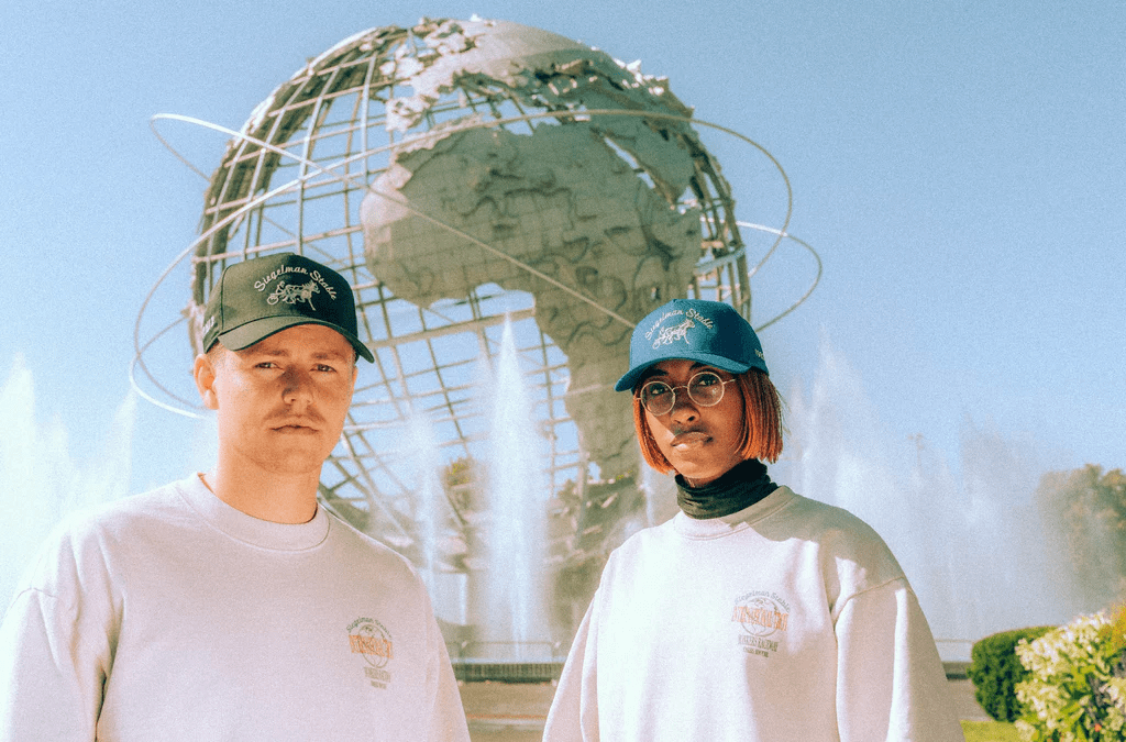 a man and woman standing next to each other wearing hats and sweatshirts
