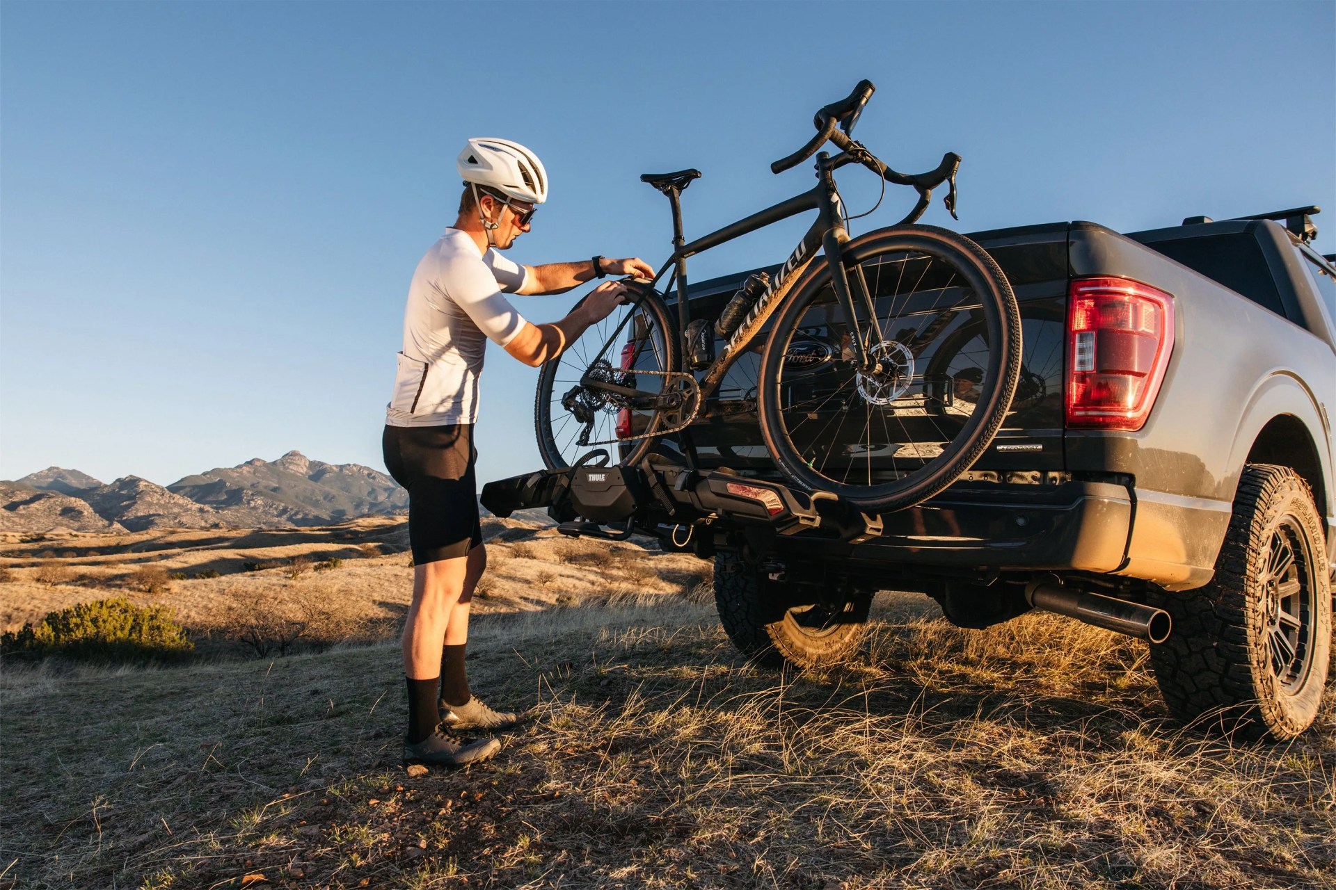 a person putting a bike on the back of a truck