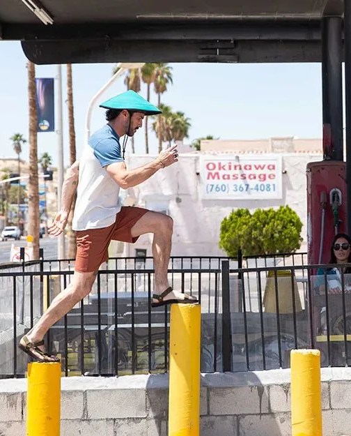 man hopping across yellow poles wearing chillba hat
