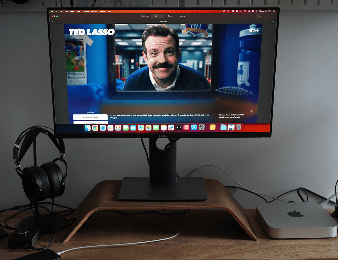 a desk with a computer monitor showing tv show ted lasso on it with a silver mac mini next to the computer