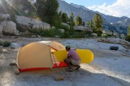 a person putting an air mattress into a tent