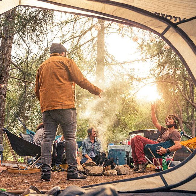 the view from inside a tent of a group of people sitting around a stone fire pit