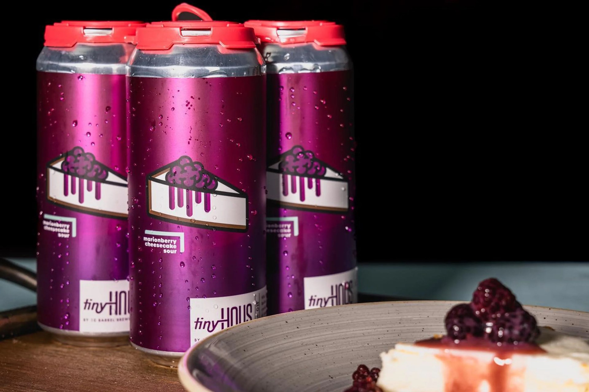 a four pack of beer on a table with pie on a plate