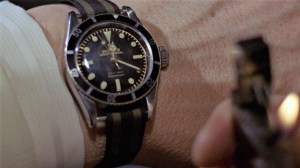 james bond in goldfinger checking his rolex submariner on a nato strap by the light of his zippo lighter