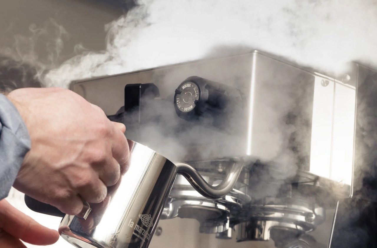 a person making steamed milk with an espresso machine