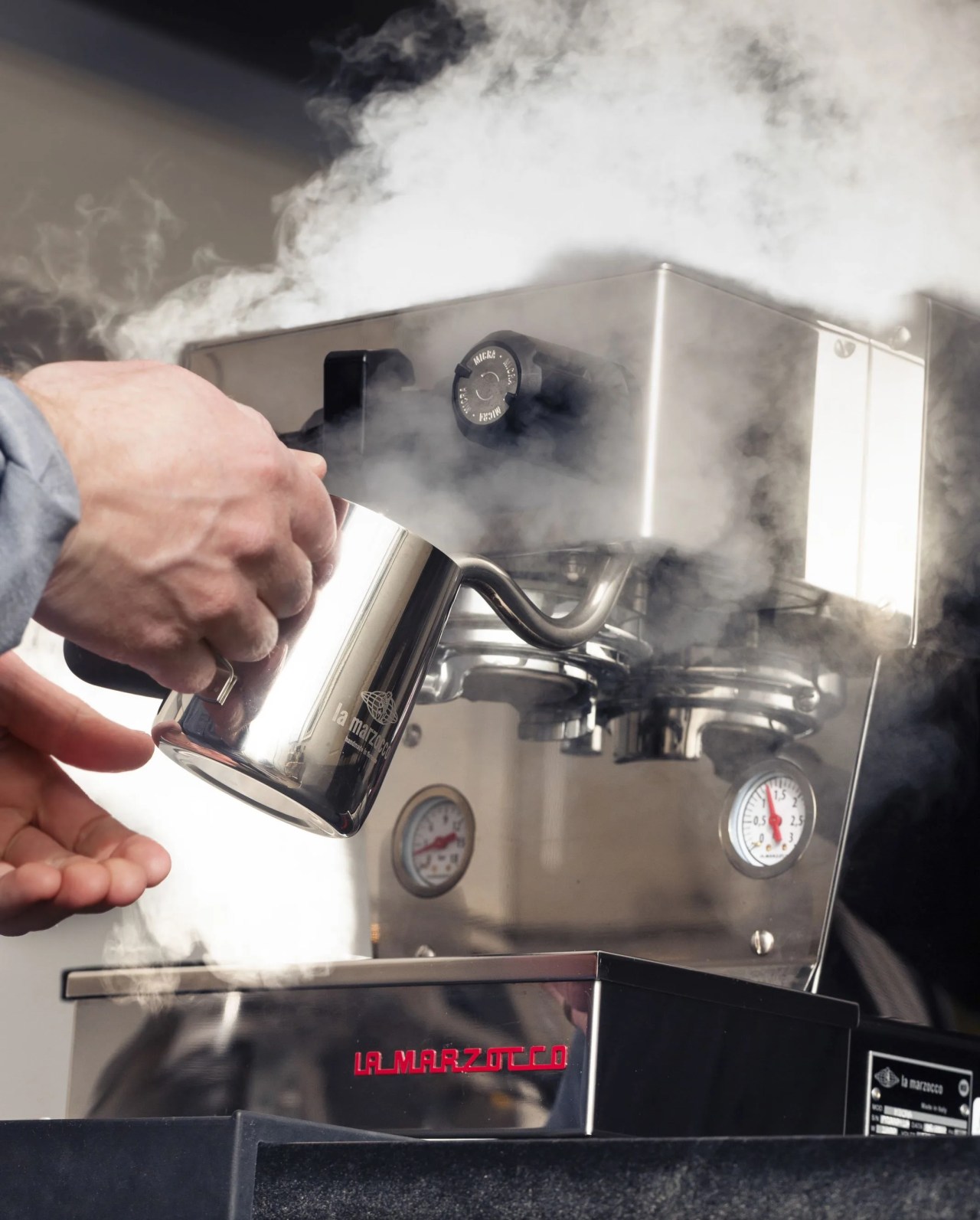 a person making steamed milk with an espresso machine