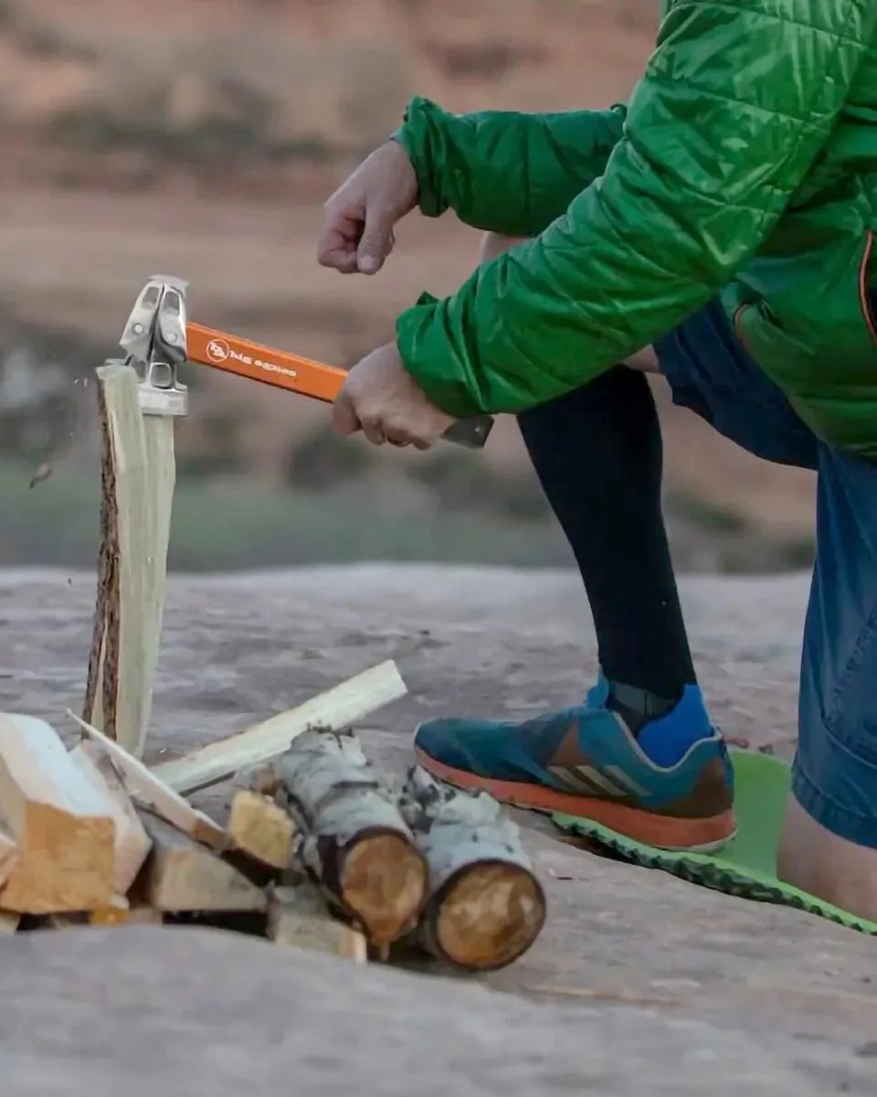 person using big agnes stake hammer or hatchet on block of wood