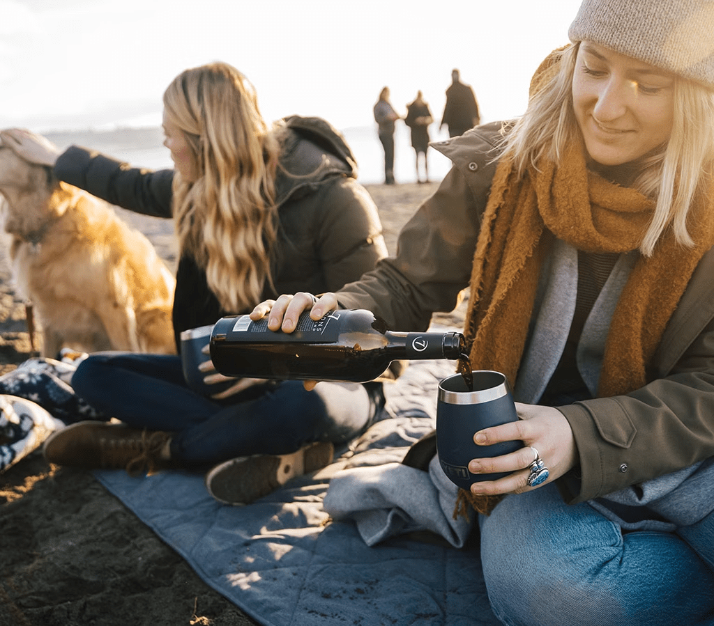 person pouring wine into yeti tumbler
