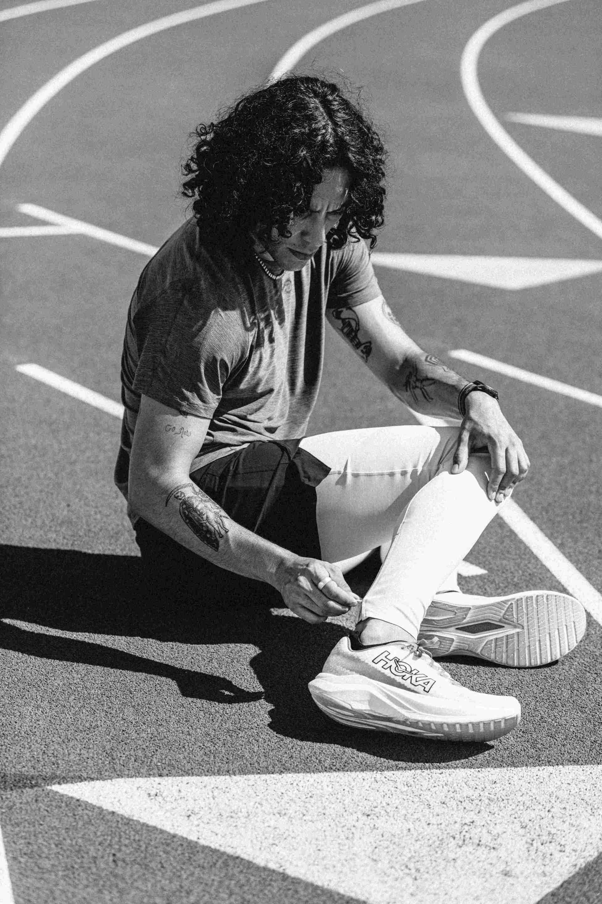 black and white image of a man sitting on a track looking at his shoes
