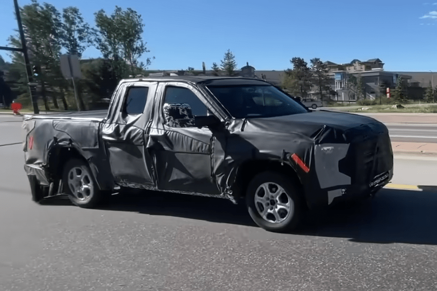 spy shot of the toyota tacoma testing on a suburban road in full camouflage