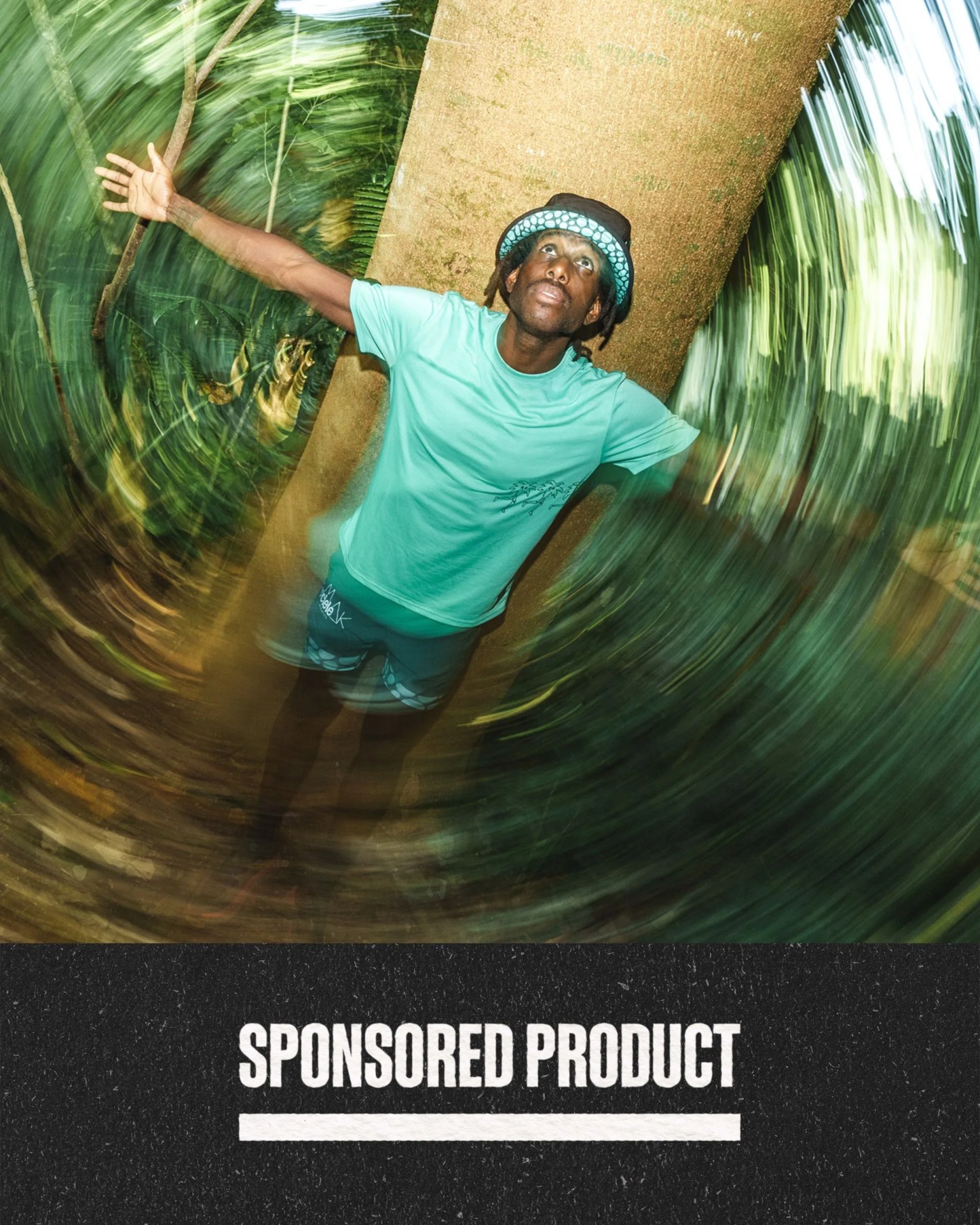 sponsored product man wearing roark ciele gear with arms spread looking up and leaning against a tree trunk